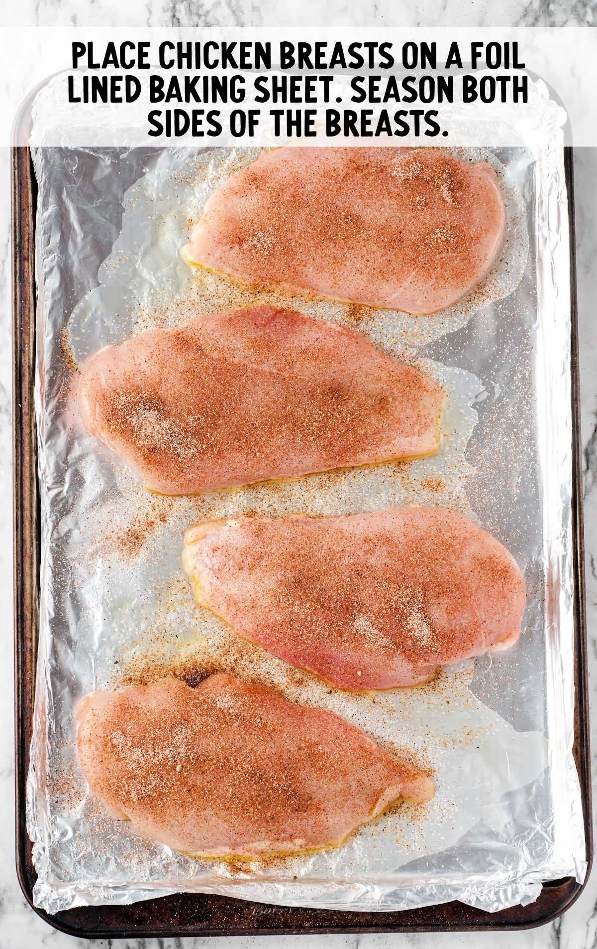 Oven Baked Chicken process shot of chicken breast placed on a foil lined baking sheet then seasoned