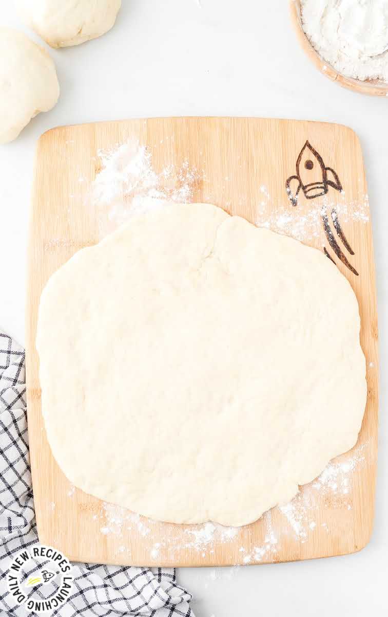overhead shot of Pizza Dough Recipe rolled out on a floured wooden board