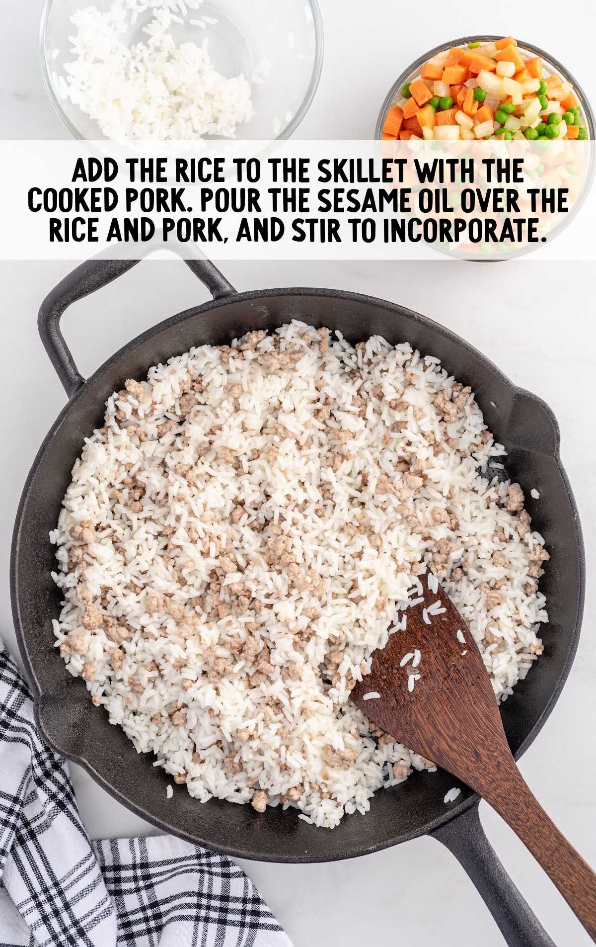 rice added to pork on a skillet and sesame oil poured over the rice and pork