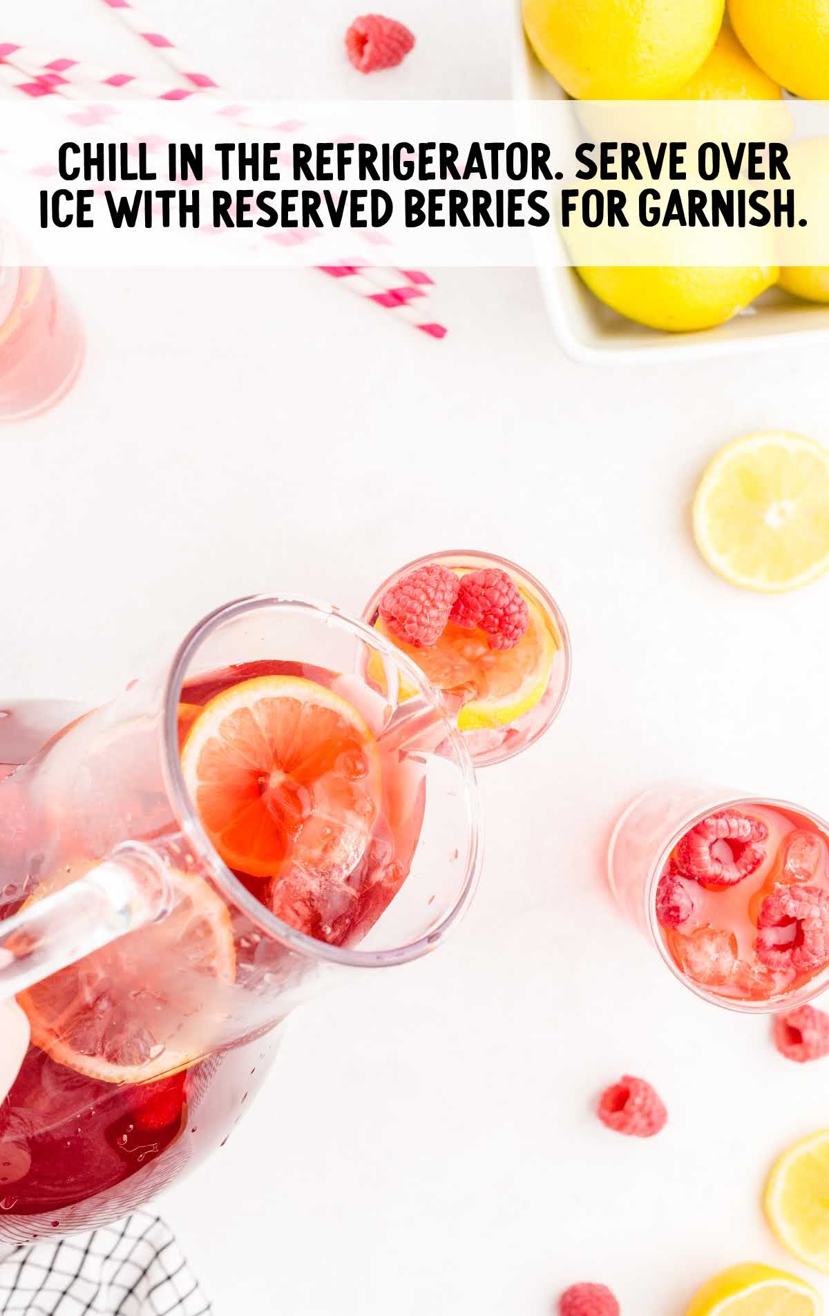 Raspberry Iced Tea being poured into a glass of lemon slices and berries