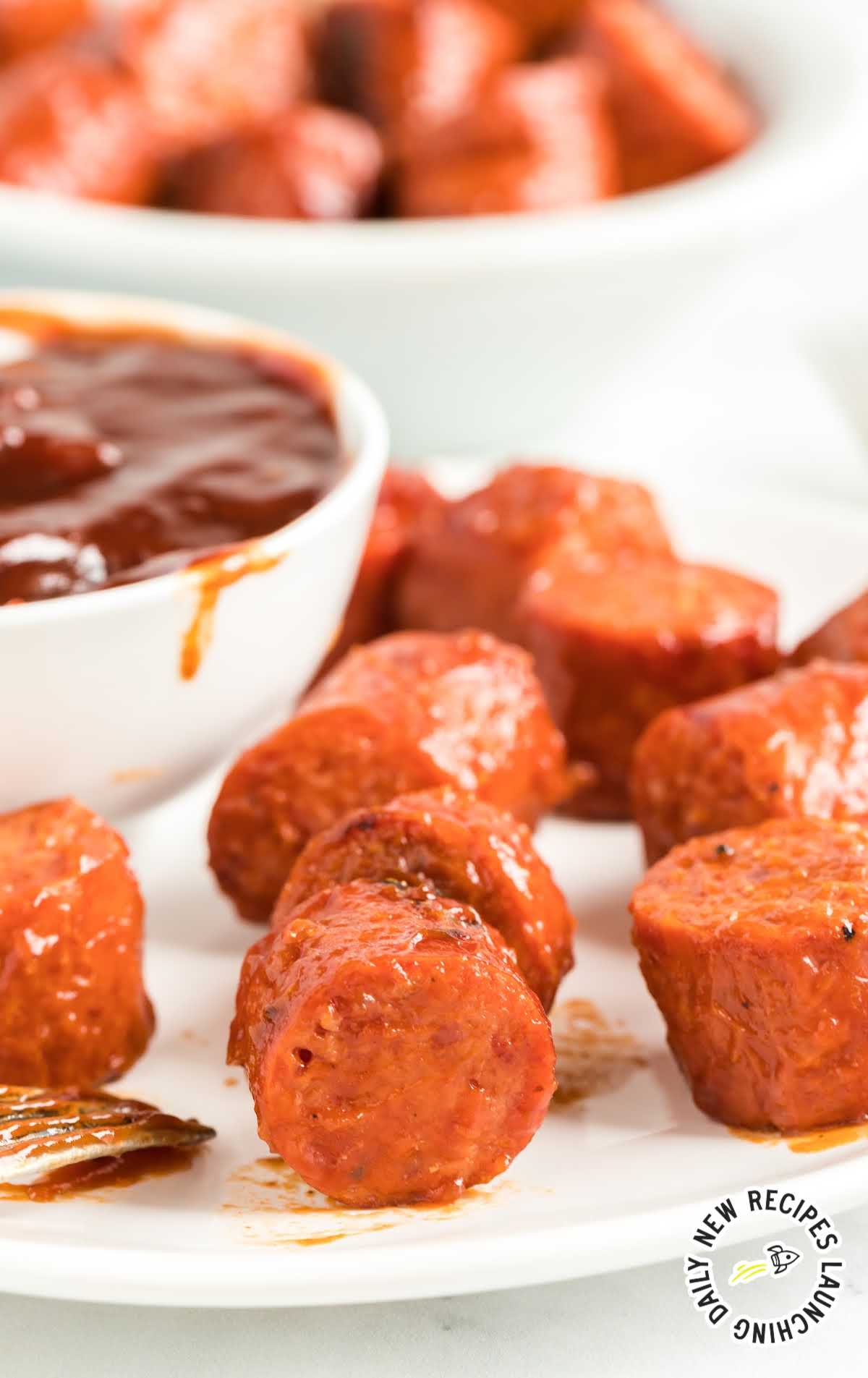 close up shot of a plate of Sausage Bites with a bowl of bbq sauce