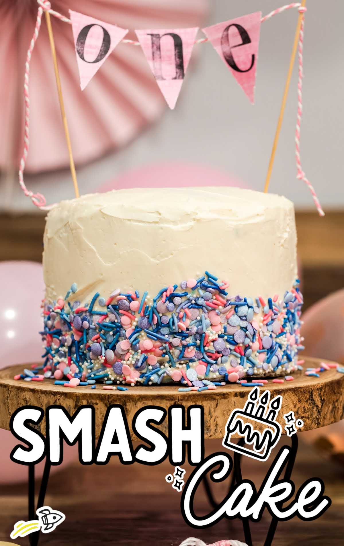 close up shot of a Smash Cake topped with a cake topper on a wooden board