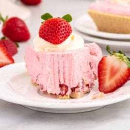 a slice of strawberry cool whip pie topped with whipped cream and a strawberry on a plate
