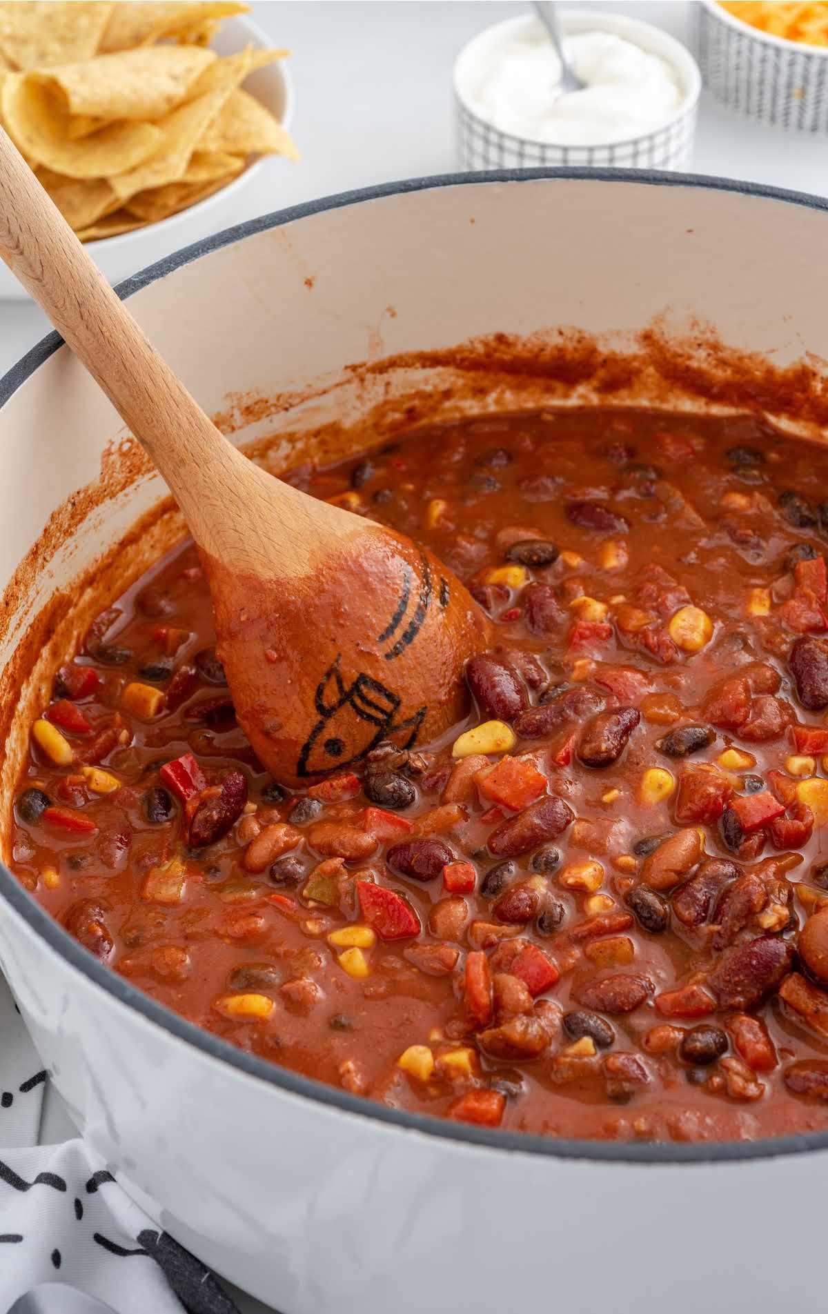 close up shot of a pot of Vegetarian Chili with a wooden spoon