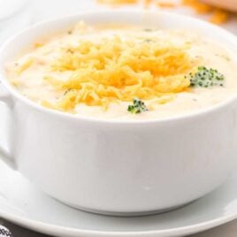 close up shot of a bowl of Broccoli and Cheese Soup topped with shredded sharp cheese