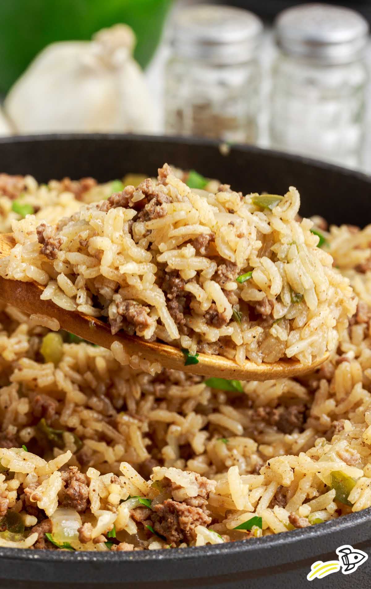 close up shot of a skillet of Dirty Rice with a large wooden spoon