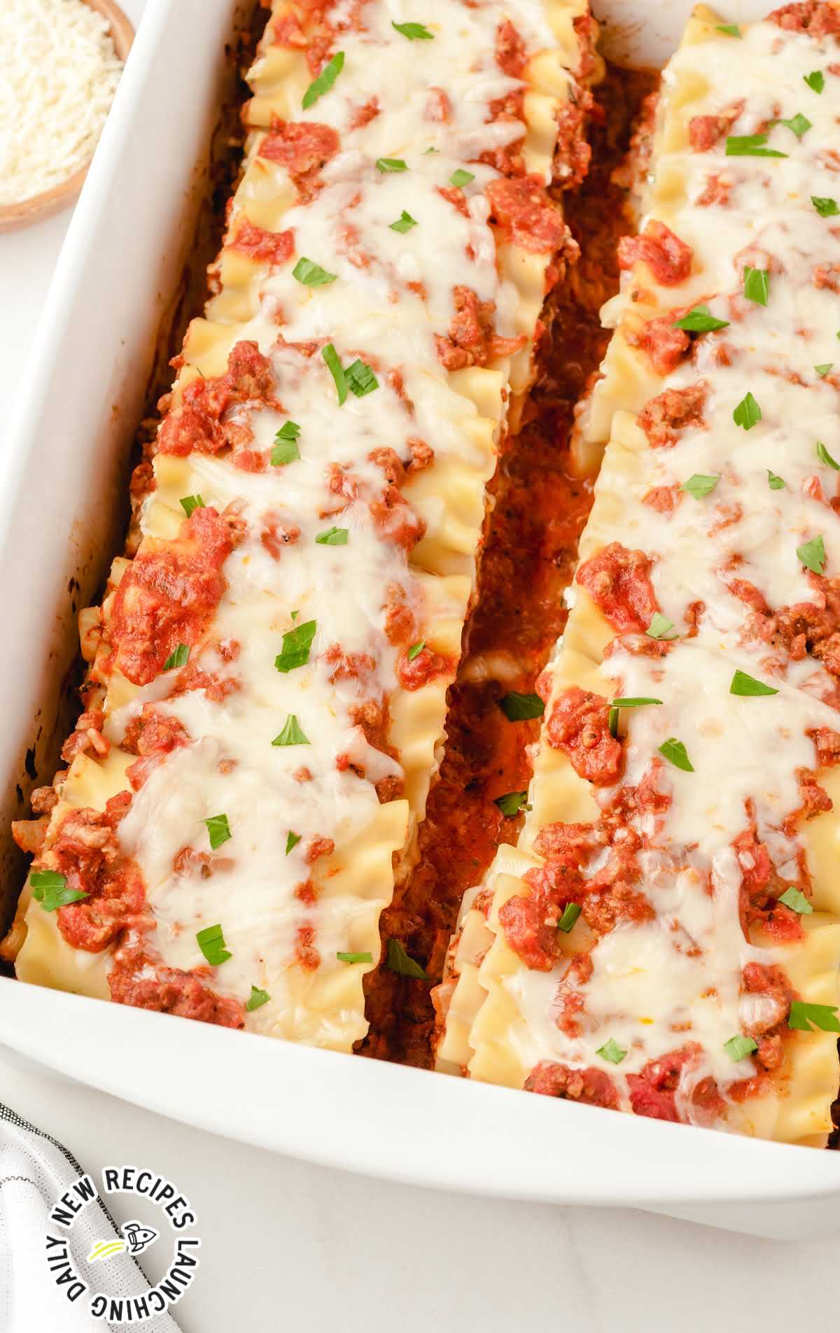 close up shot of Lasagna Roll Ups topped with parsley in a baking dish