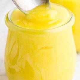 close up shot of a jar of Lemon Curd with a spoon dipped into it