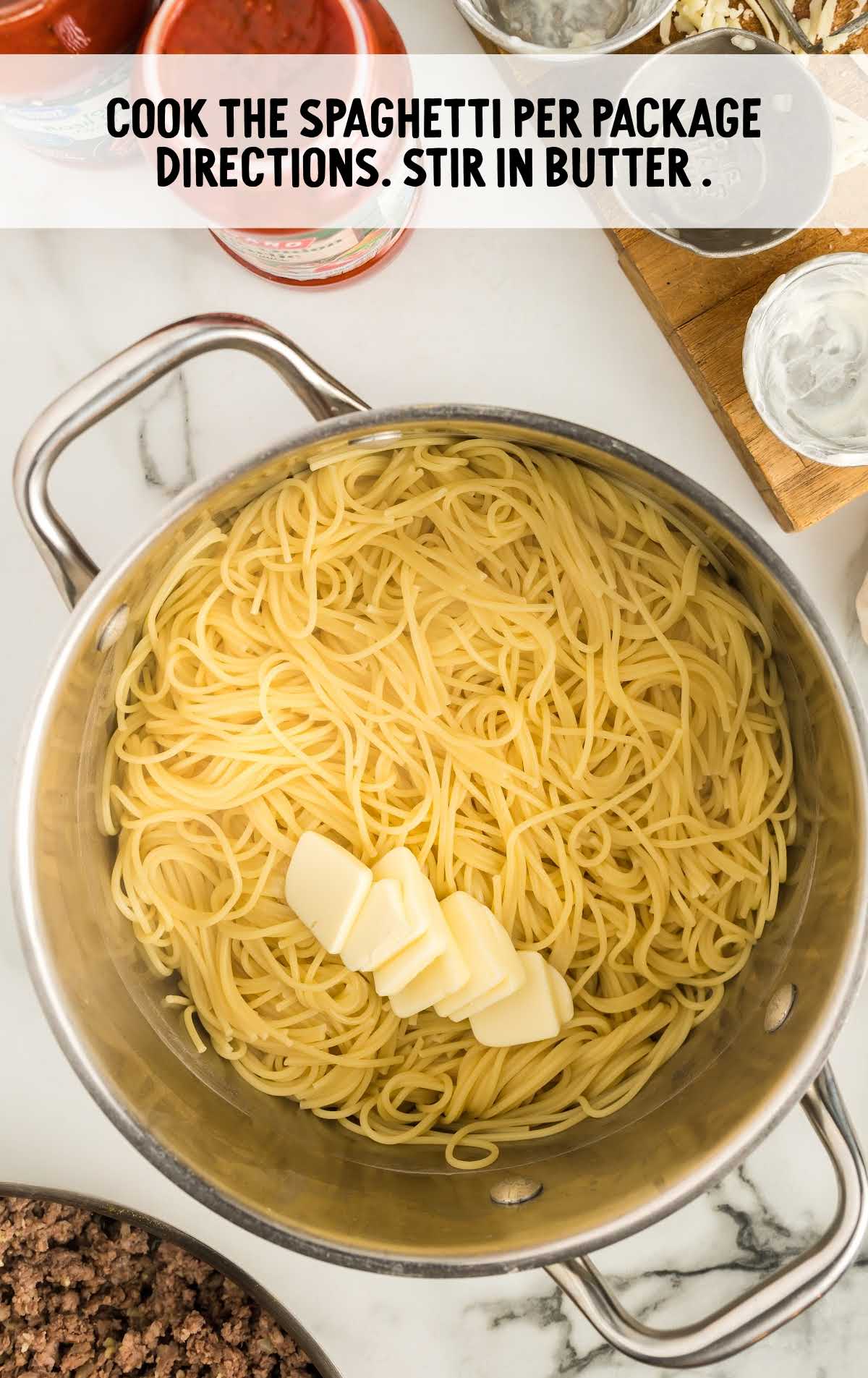 cooked spaghetti in a pot with slices of butter