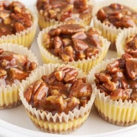 close up shot of a serving stand of cheesecake bites topped with pecans