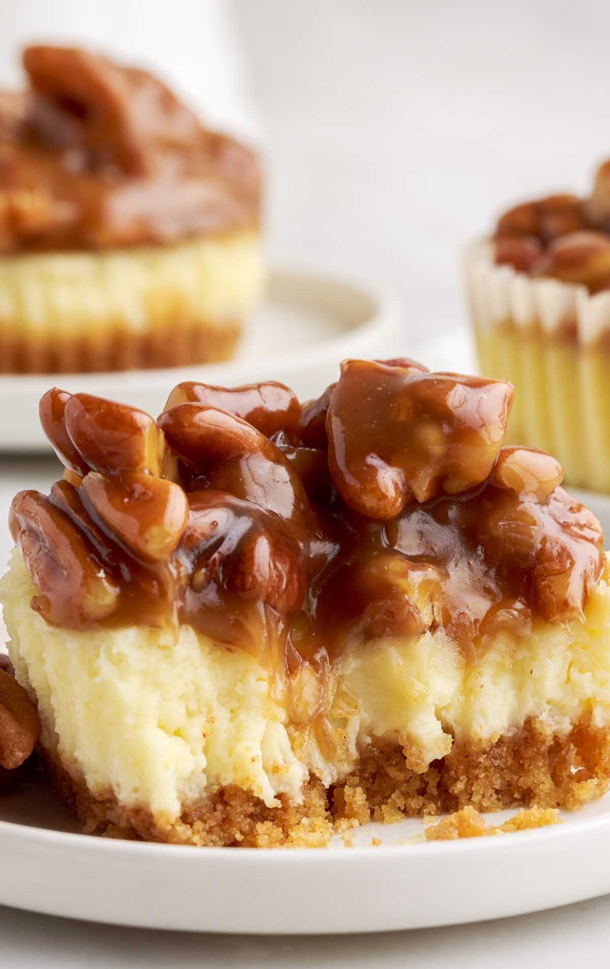 close up shot of a cheesecake bite topped with pecans on a plate
