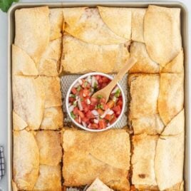 overhead shot of sheet pan full of tacos with a bowl of salsa