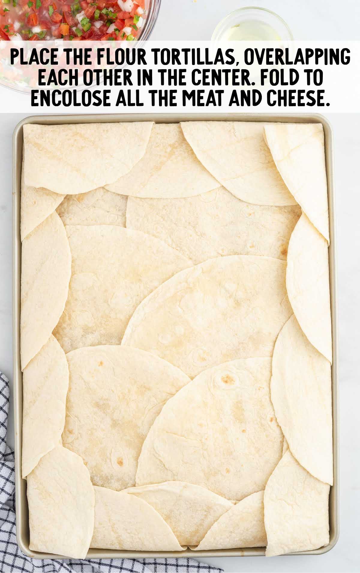 flour tortillas folded closed on a sheet pan