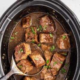 close up overhead shot of a slow cooker full of beef tips garnished with parsley