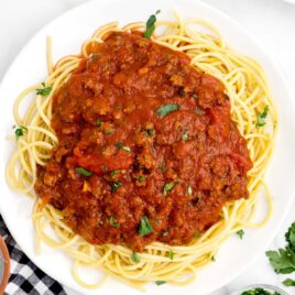close up overhead shot of a plate of Spaghetti noodles topped with Meat Sauce and garnished with parsley