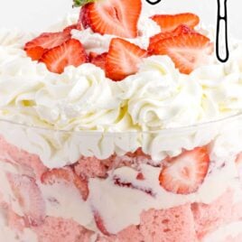close up shot of a big serving bowl of trifle topped with chopped strawberries