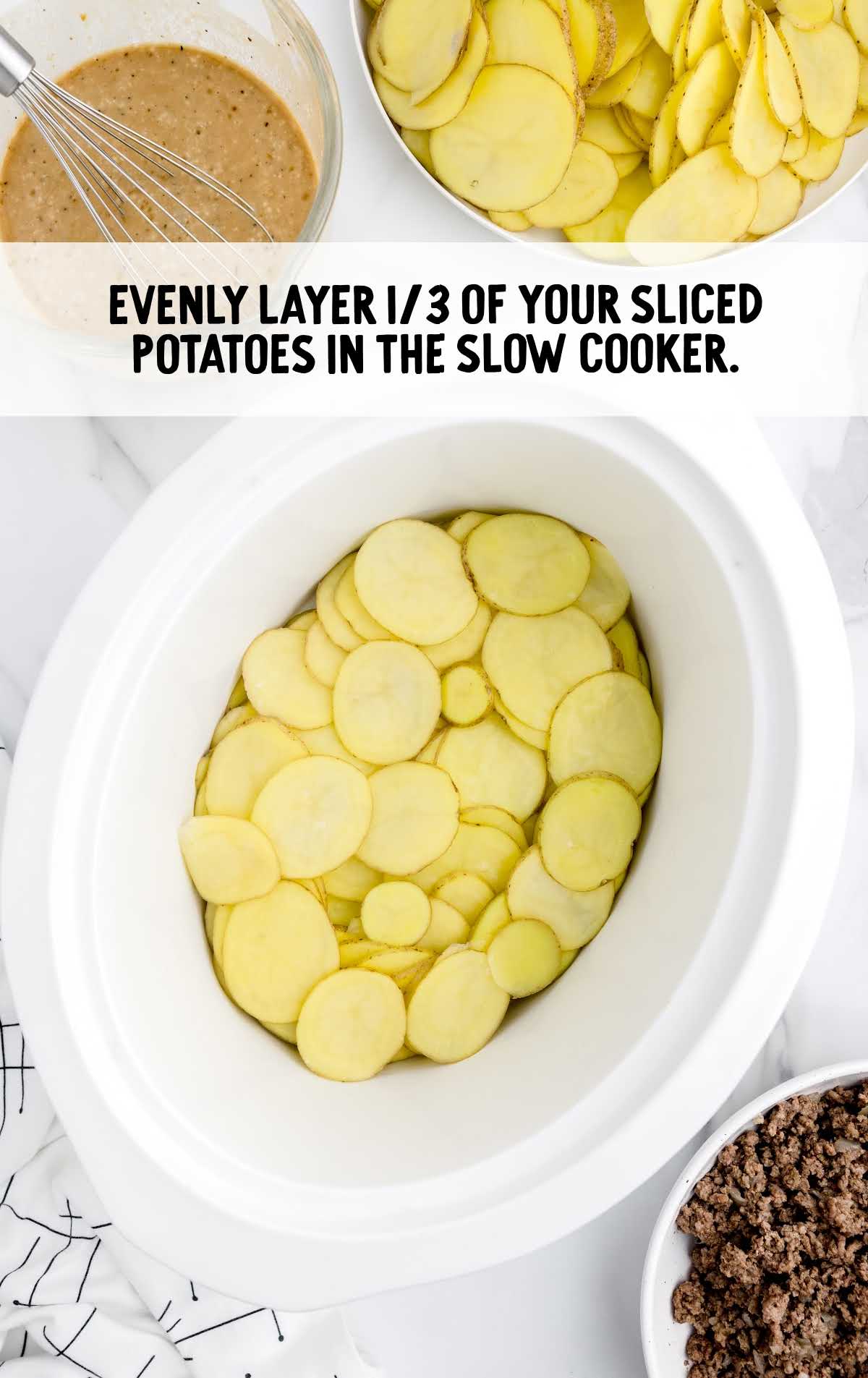 slices of potatoes layered in the bottom of a slow cooker
