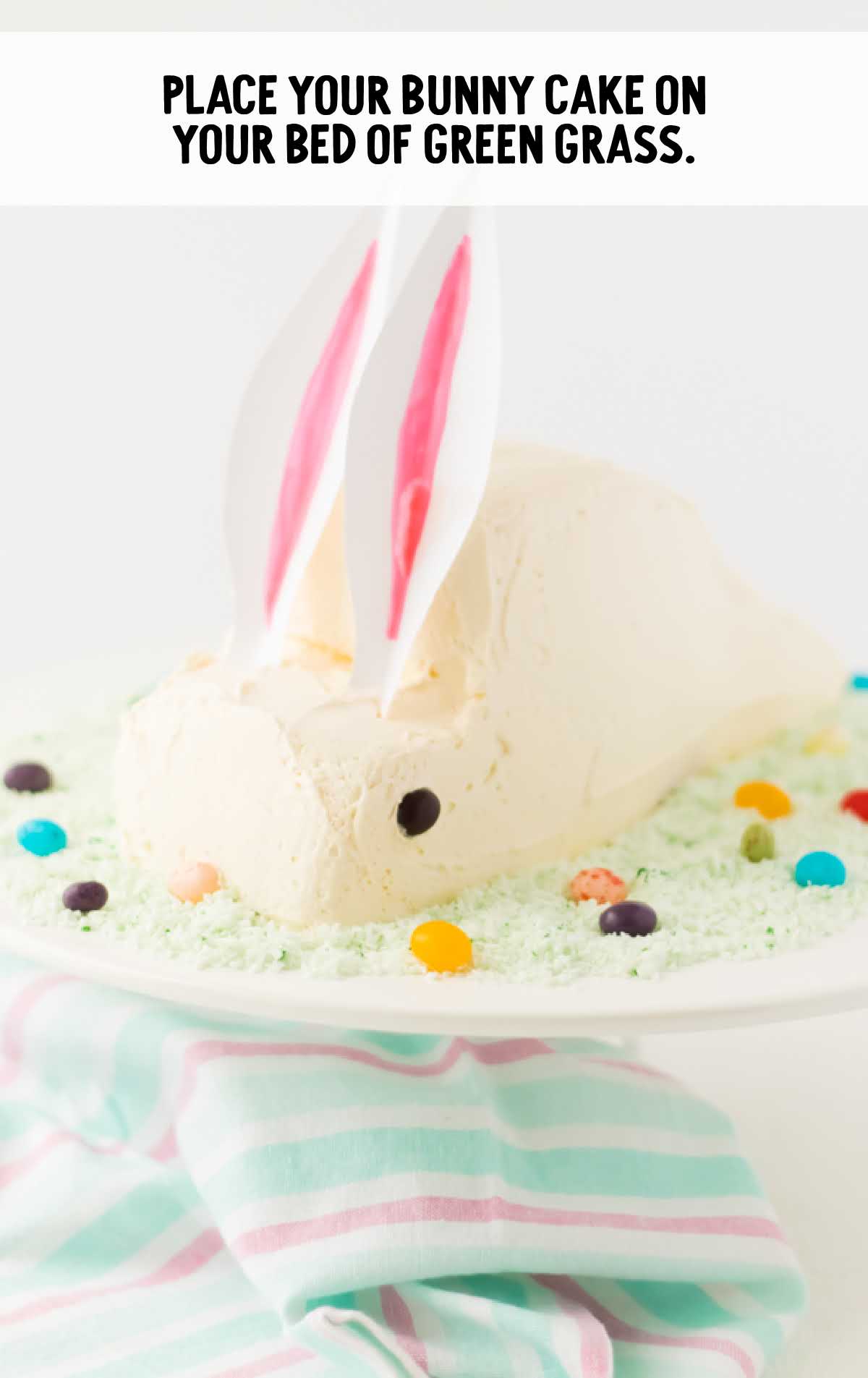 bunny placed on a bed of green grass on a cake stand