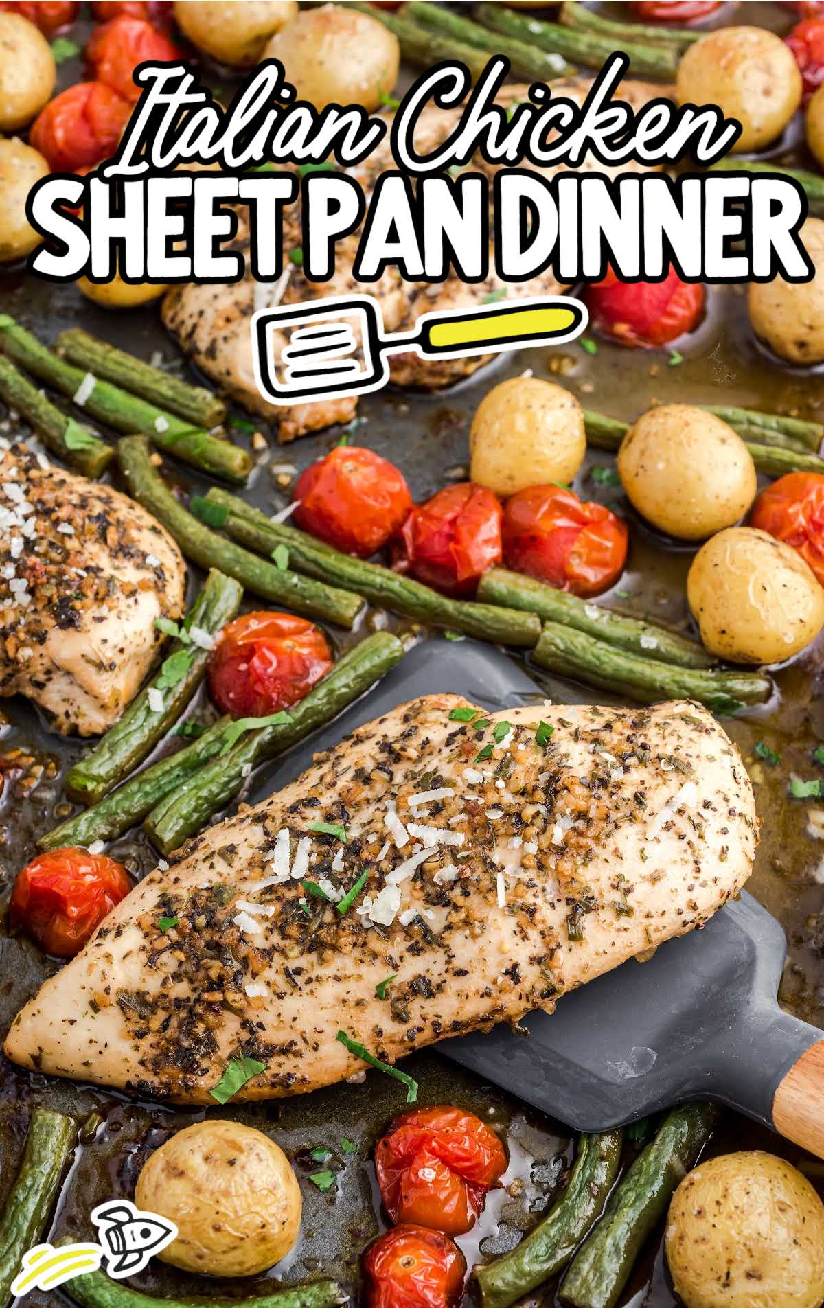 close up shot of a sheet pan full of baked chicken, potatoes, tomatoes, and green beans