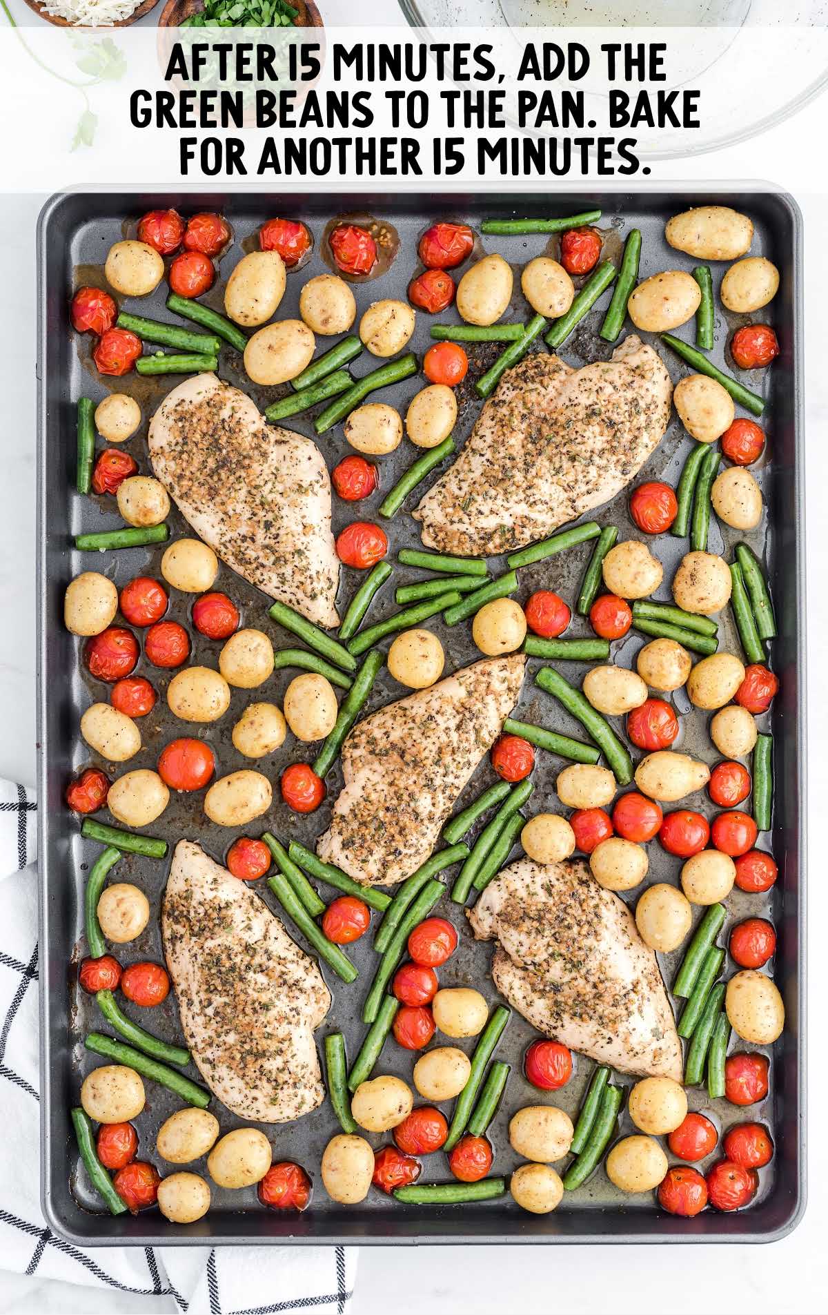 a sheet pan of chicken breast, tomatoes, green beans, and potatoes