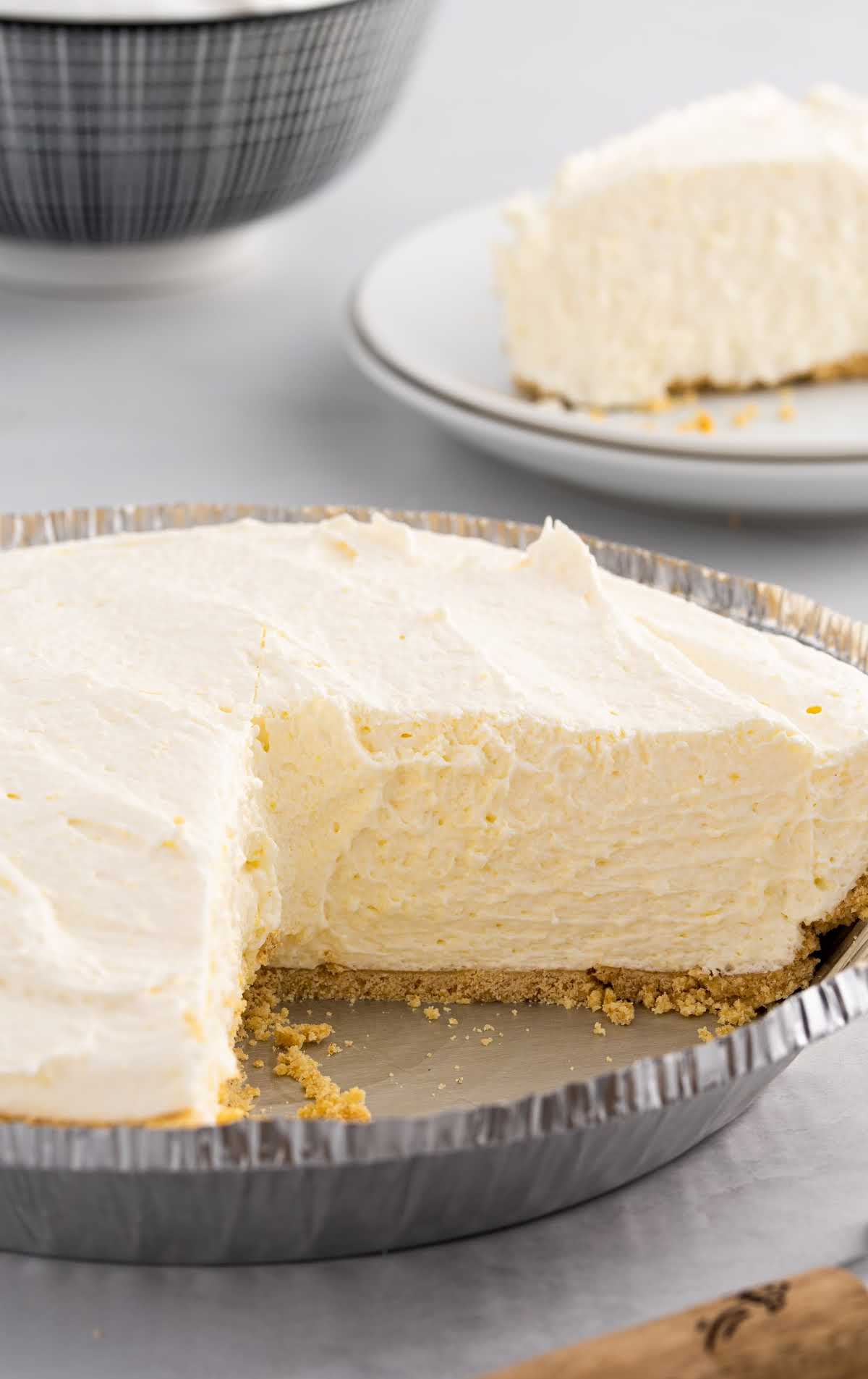 close up shot of a whole vanilla cool whip pie with a slice missing