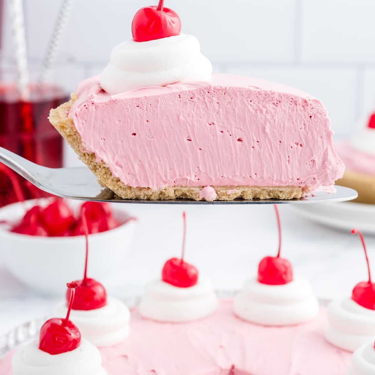 close up shot of a slice of pie topped with whipped cream and a cherry on a spatula
