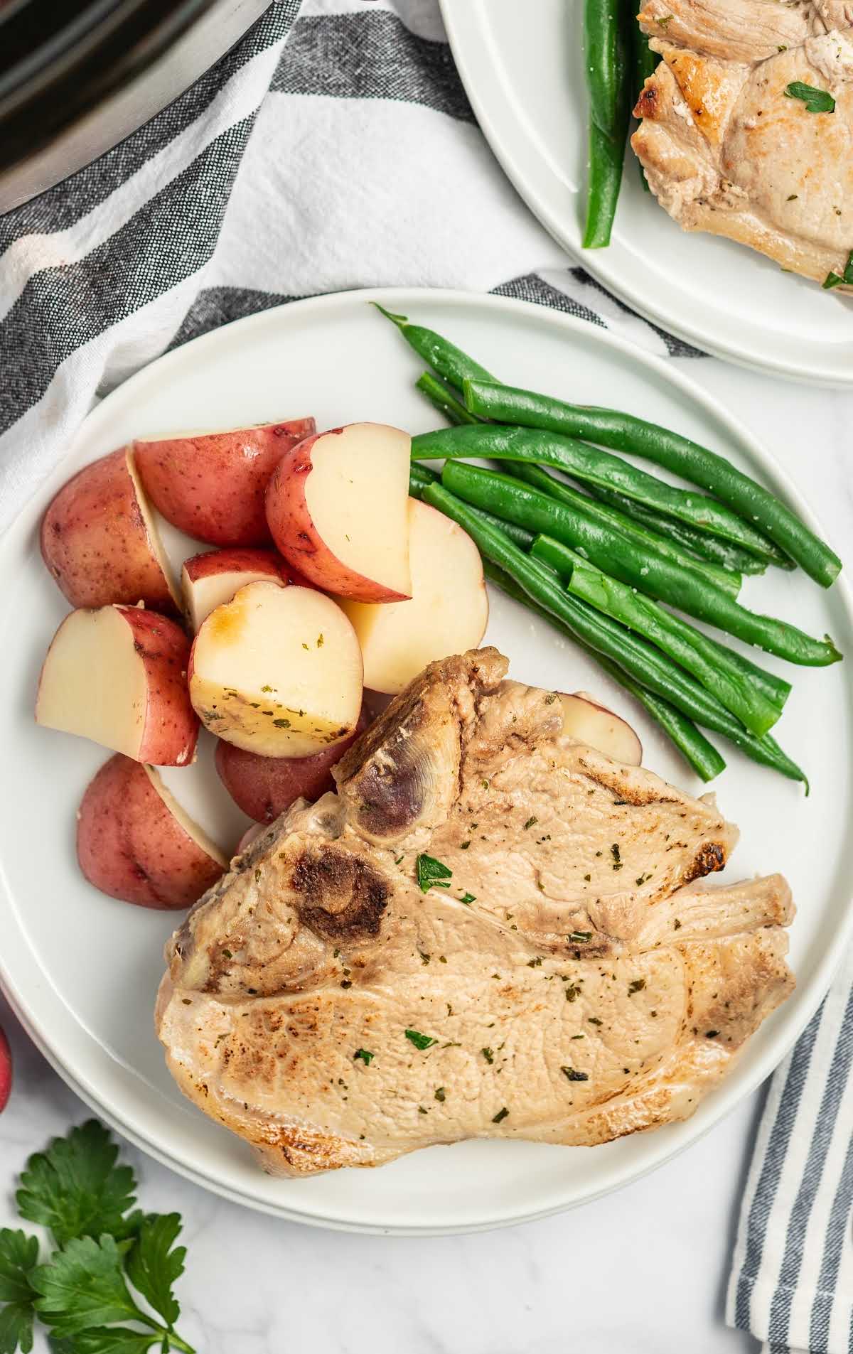 overhead shot of a plate of pork chops served with diced red potatoes and green beans