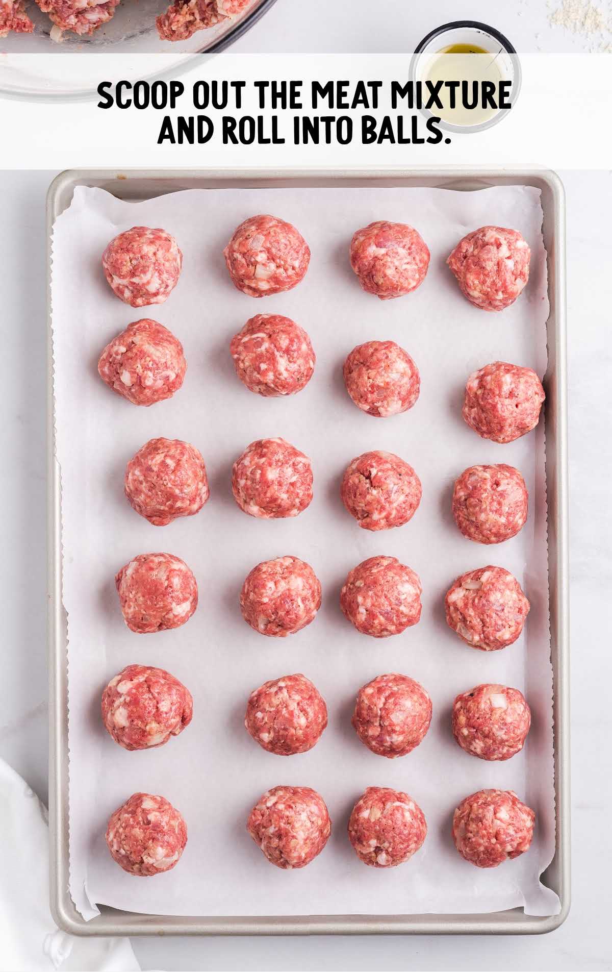 meatball mixture rolled into balls then scooped on a parchment lined baking sheet