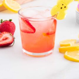 close up shot of a cocktail in a glass with sliced strawberries and lemons garnished with PEEPS Bunny candy