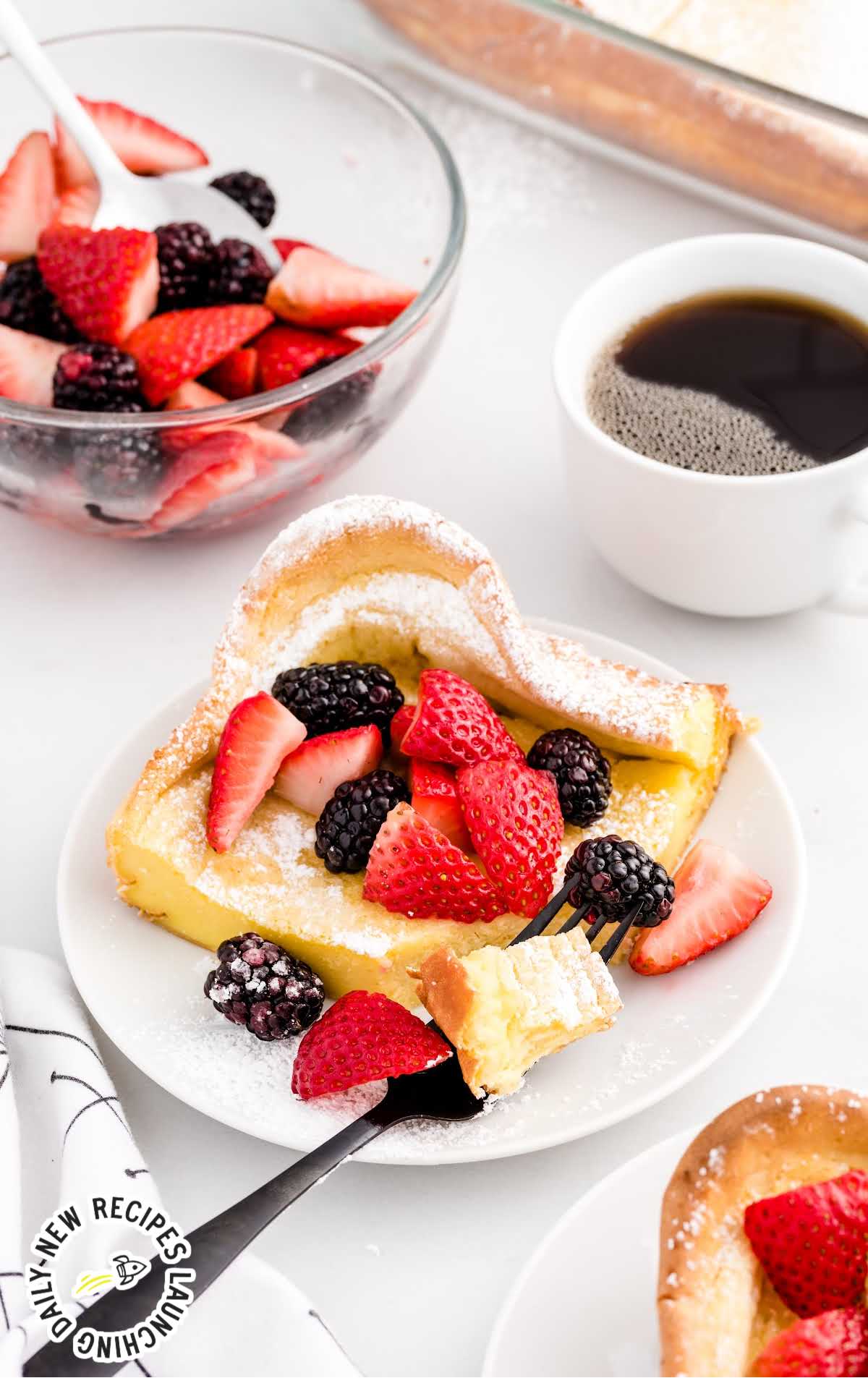 a piece of dutch baby topped with diced strawberries and blackberries on a plate