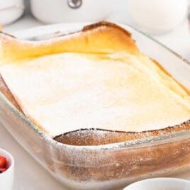 close up shot of a dutch baby sprinkled with powdered sugar in a pan
