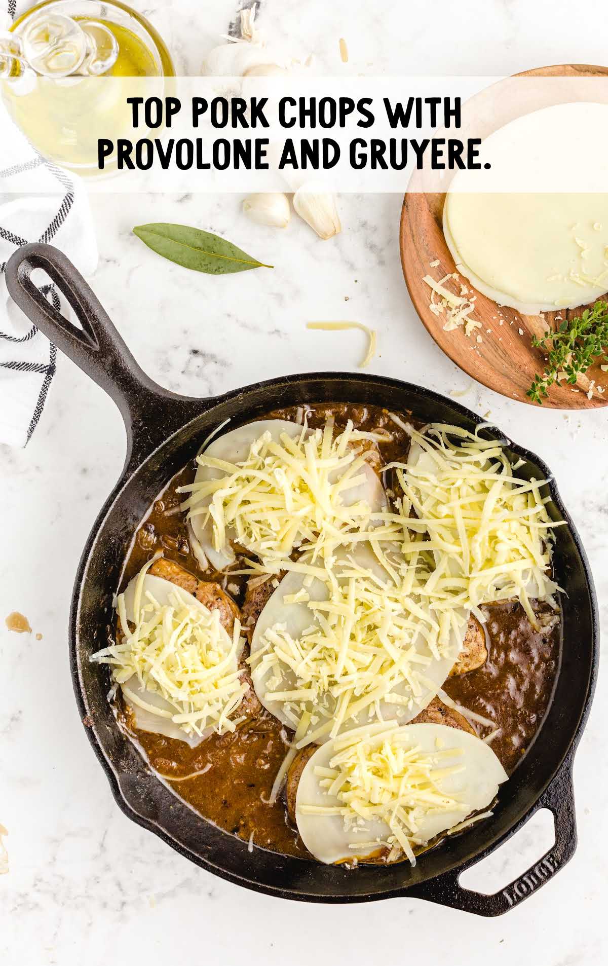 pork chops topped with provolone and gruyere in a skillet