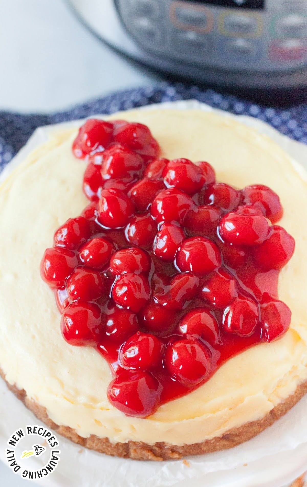 close up shot of a whole cheesecake topped with cherry pie filling