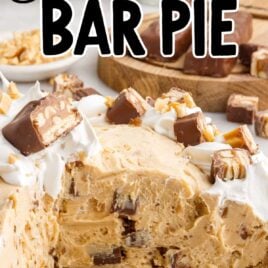 close up shot of a baking dish of pie topped with pieces of snickers with a slice missing