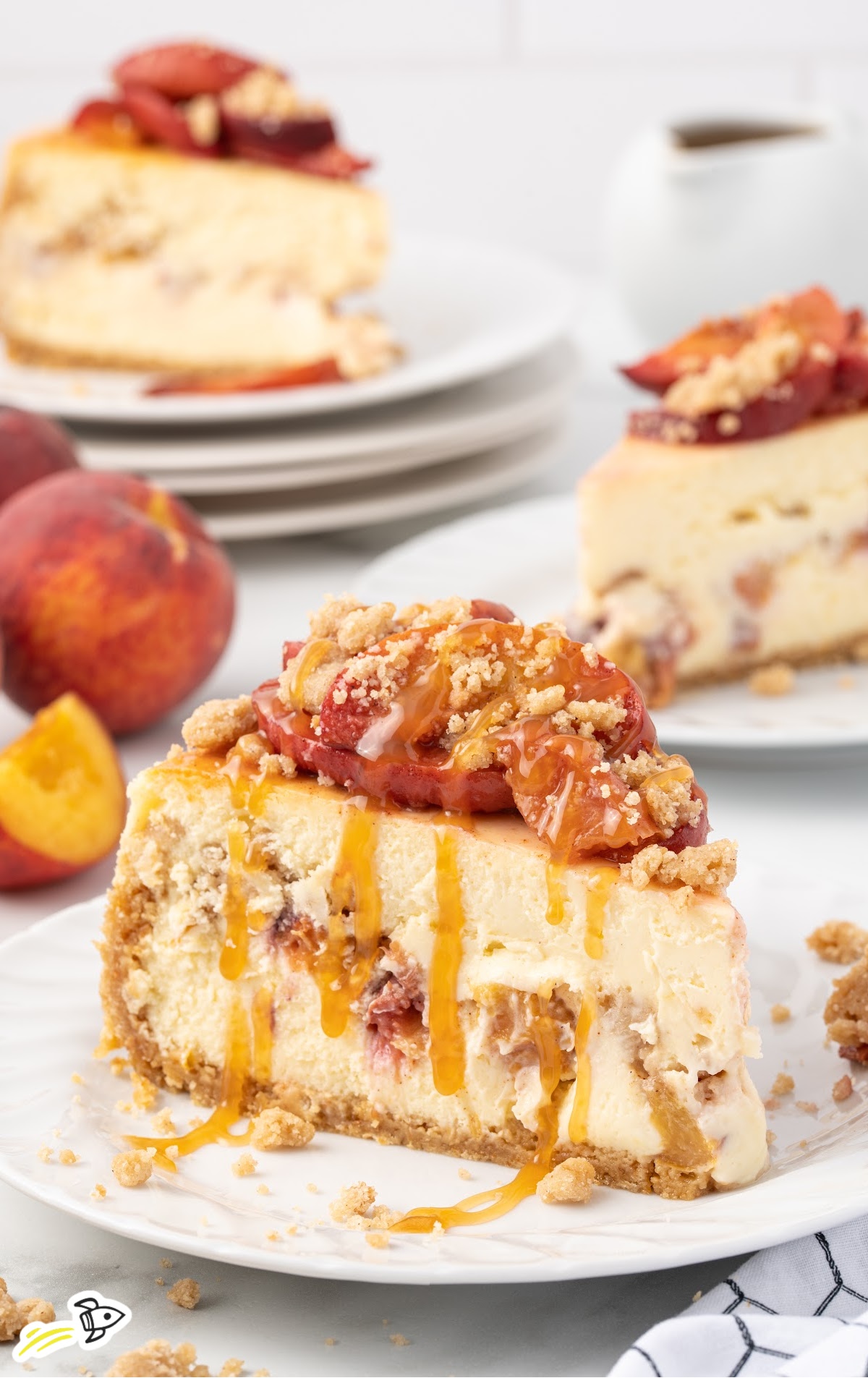 A slice of Peach Cobbler Cheesecake is on a small white plate.