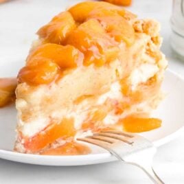 close up shot of a slice of peach cheesecake on a plate