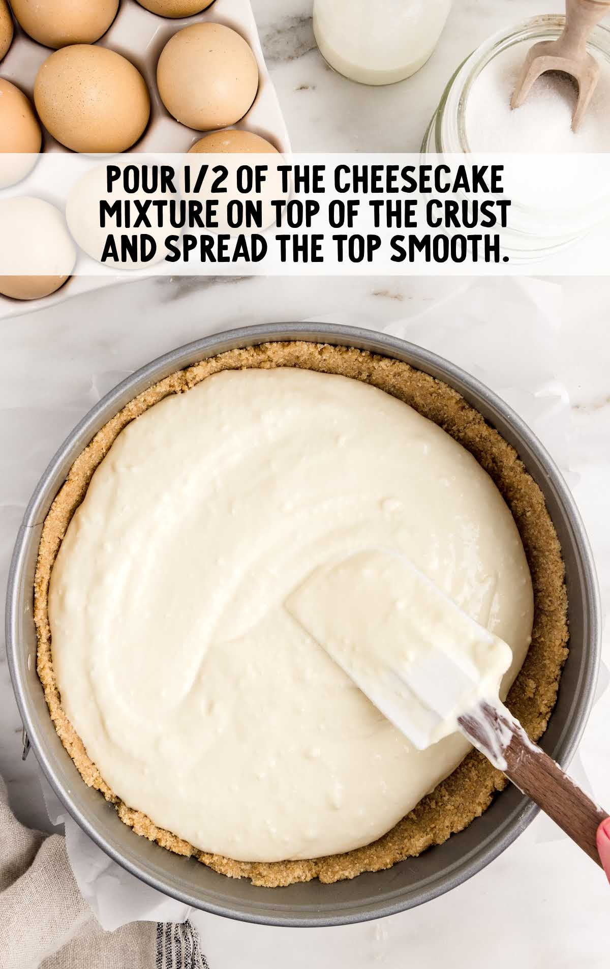 cheesecake mixture poured on top of the graham cracker crust in a pan