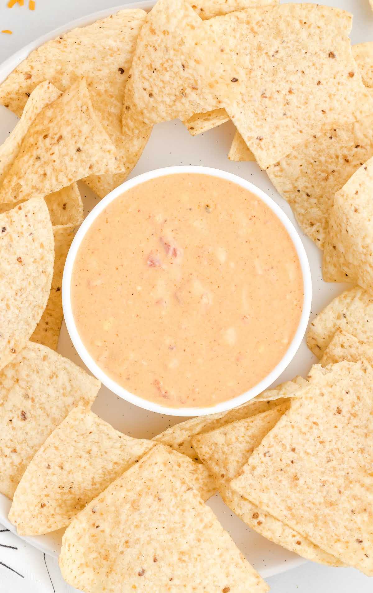 close up overhead shot of a bowl of queso dip surrounding chips