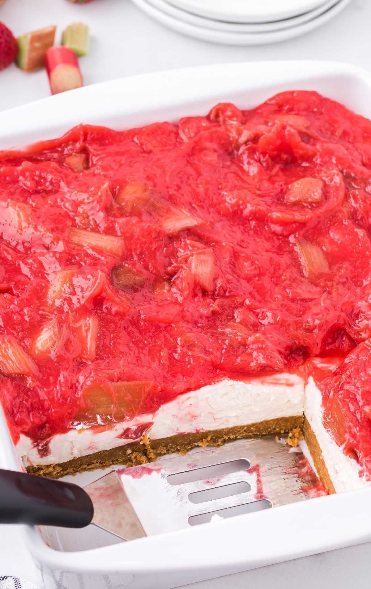 close up shot of a baking dish of Strawberry Rhubarb Cheesecake with slices missing