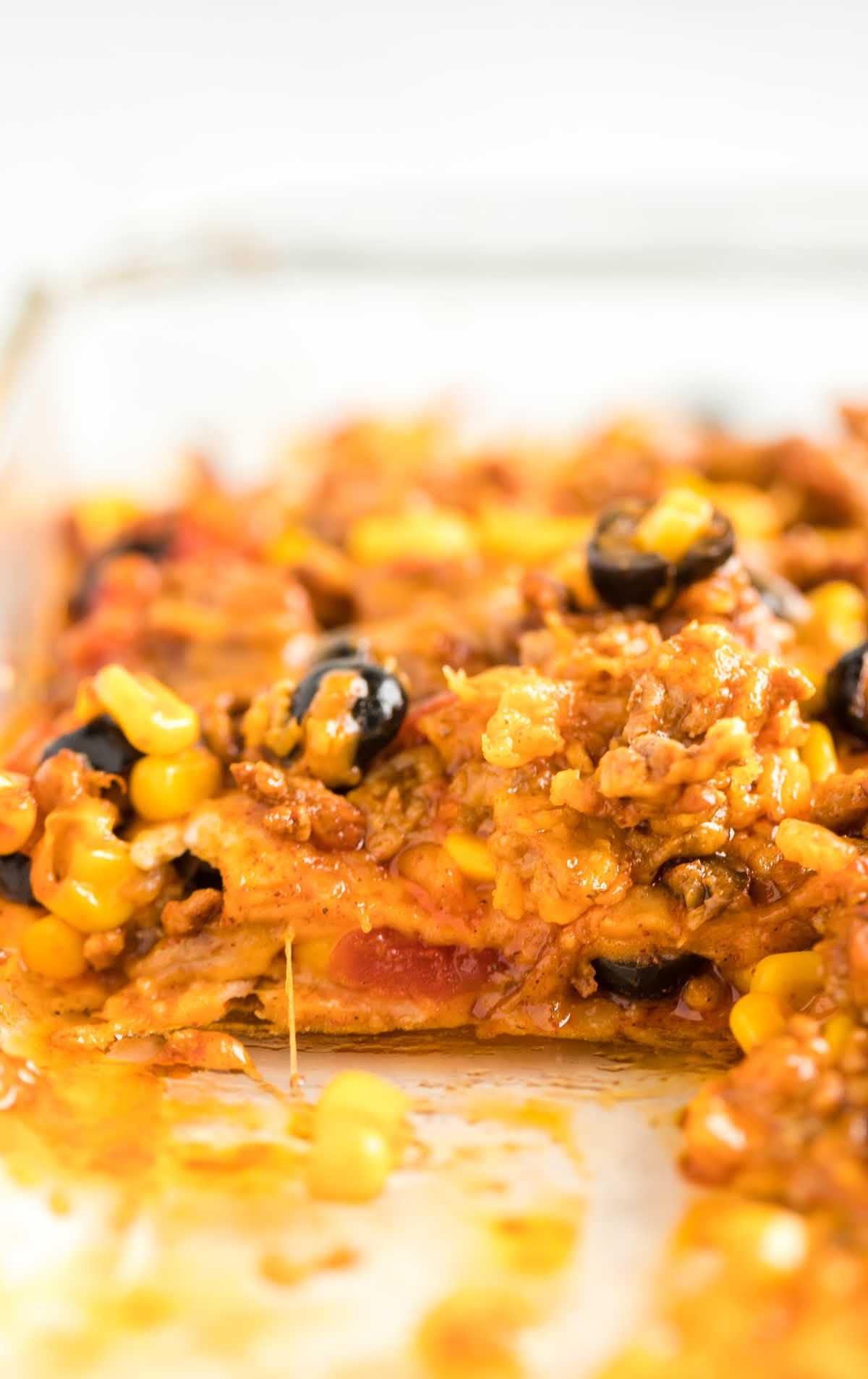 close up shot of a casserole full of taco bake with a piece missing
