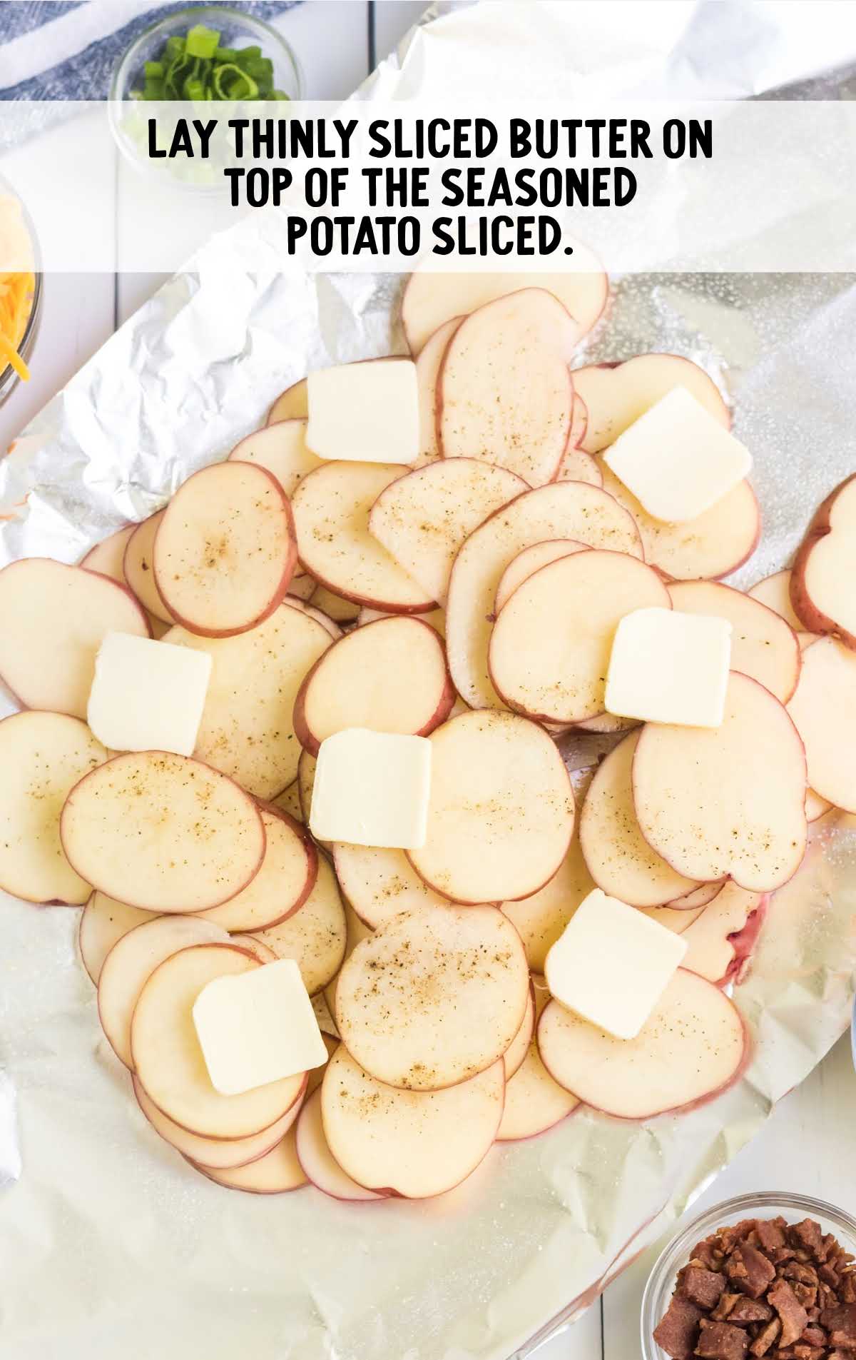 slices of butter placed on top of seasoned potato slices
