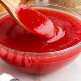 close up shot of a bowl of homemade sweet and sour sauce with a spoonful of sauce
