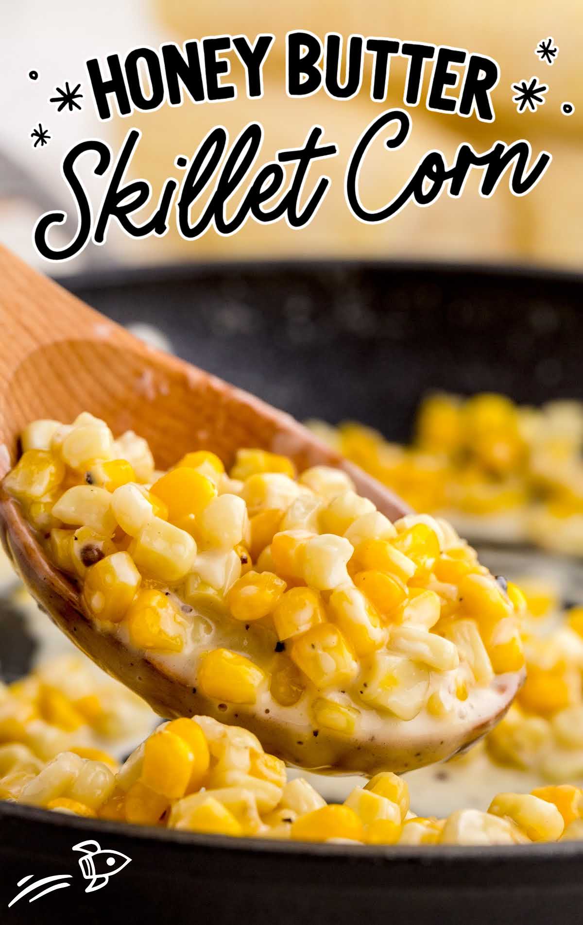 close up shot of corn in a skillet and a spoonful on a large wooden spoon