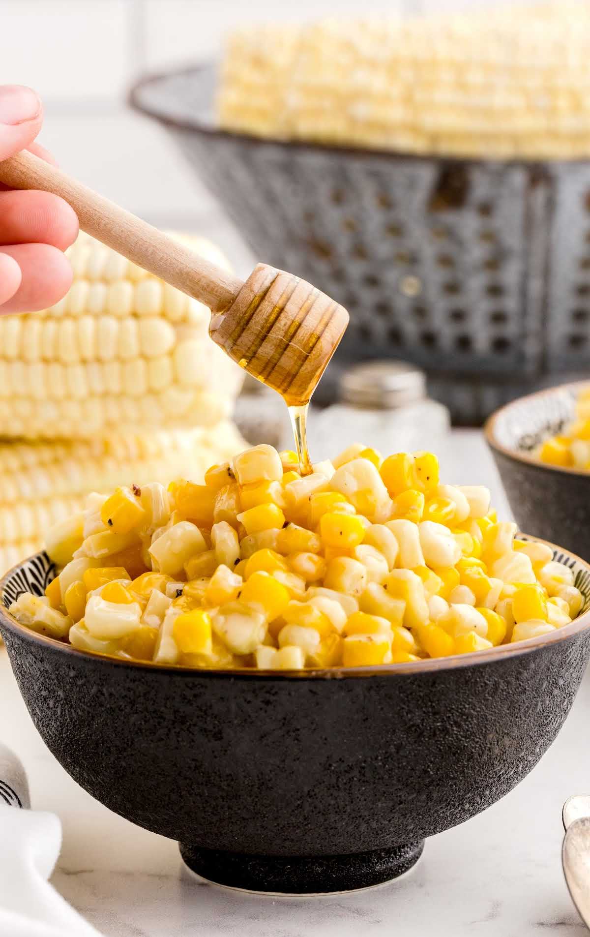 close up shot of a bowl of corn with honey being drizzled on top