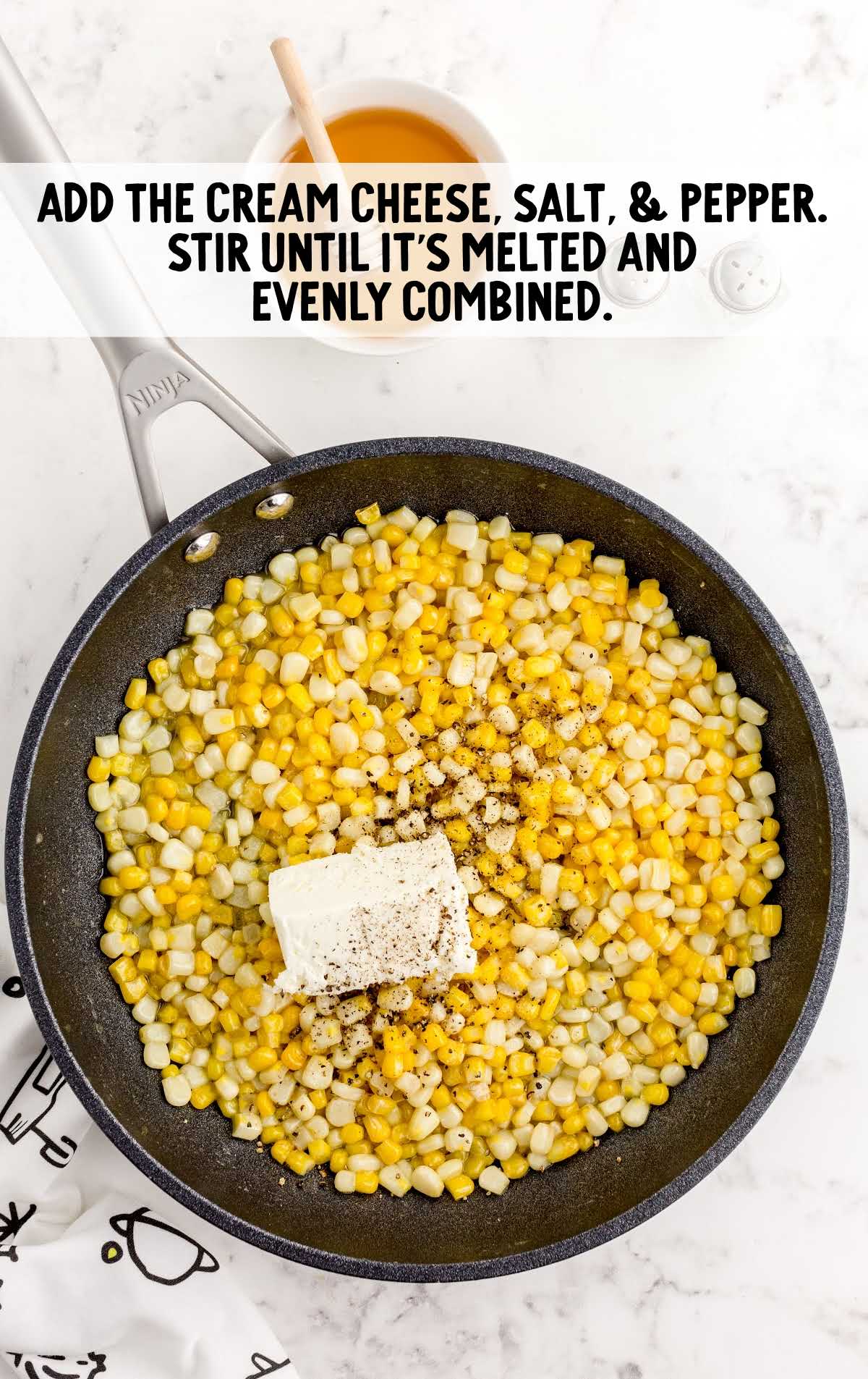 cream cheese, salt, and pepper added to the skillet of cooked corn