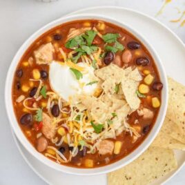 over head shot of 7 Can Chicken Taco Soup topped with sour cream and chips in a bowl