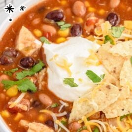 close up shot of 7 Can Chicken Taco Soup topped with sour cream and chips in a bowl