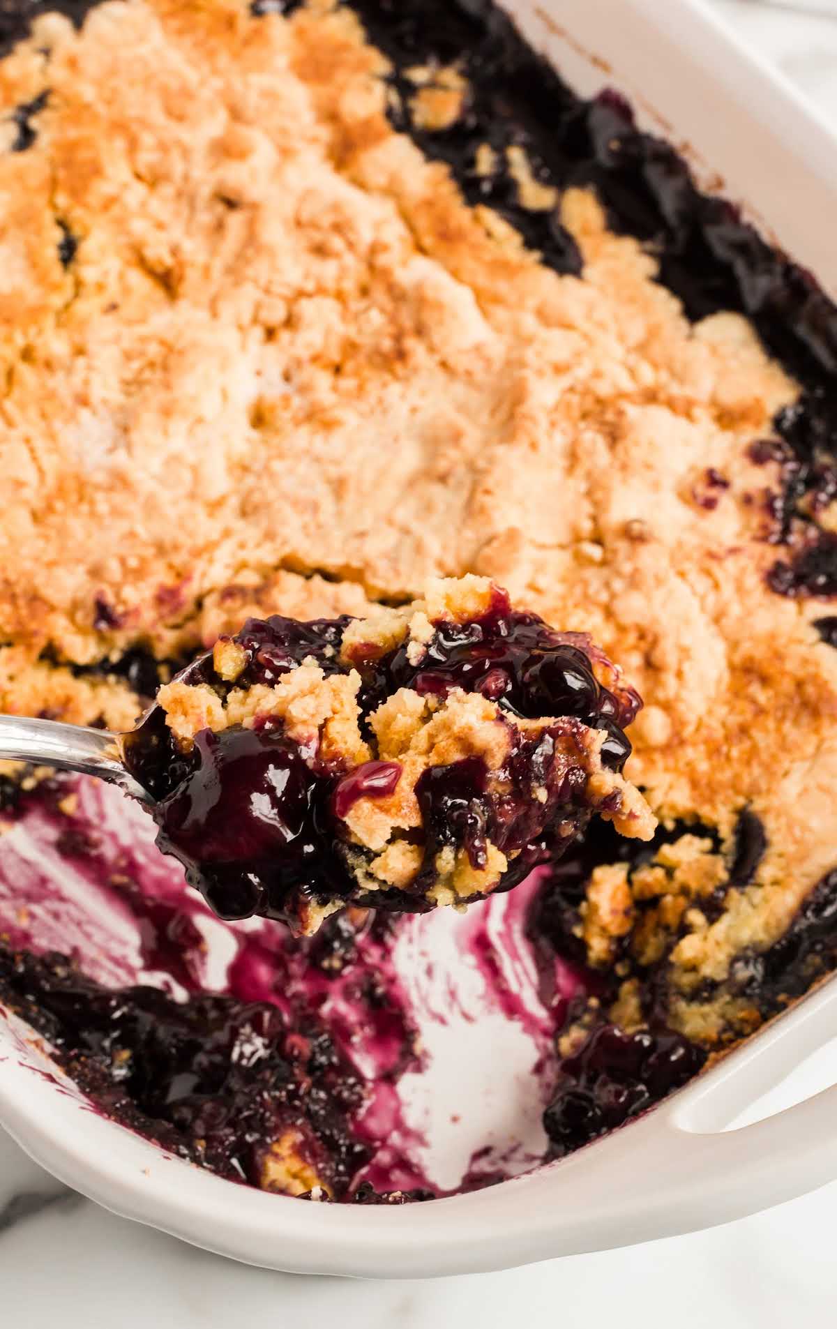 close up shot of a baking dish of Blueberry Dump Cake with a piece missing