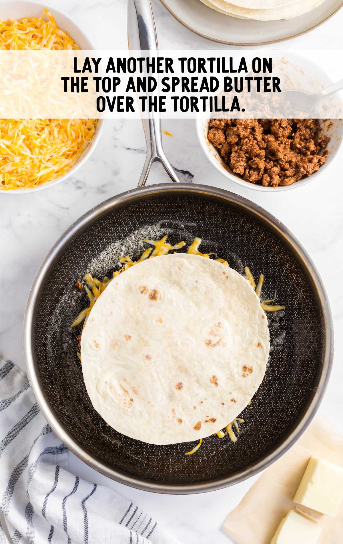 tortilla placed on top of the cheese mixture in the skillet