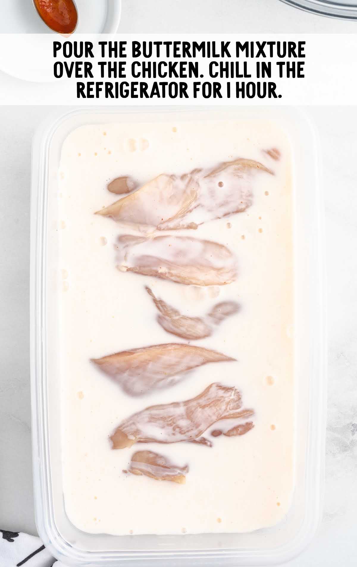 pieces of chicken in a container of buttermilk mixture
